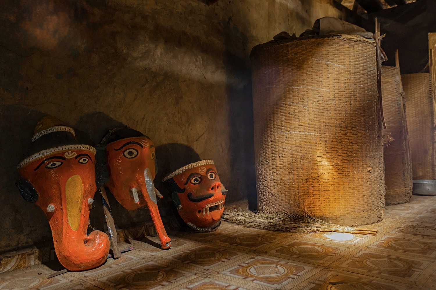 Painted tribal deities beside grain baskets in a Dangi home