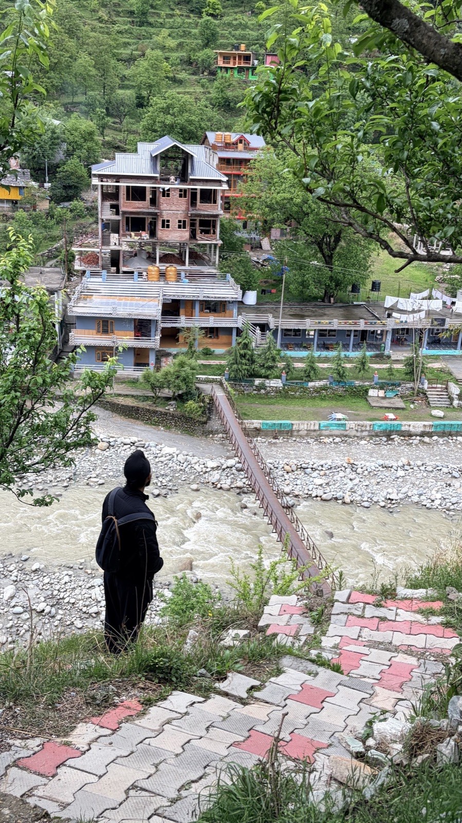 A traveller pausing on the hillside climb, the valley and river laid out below