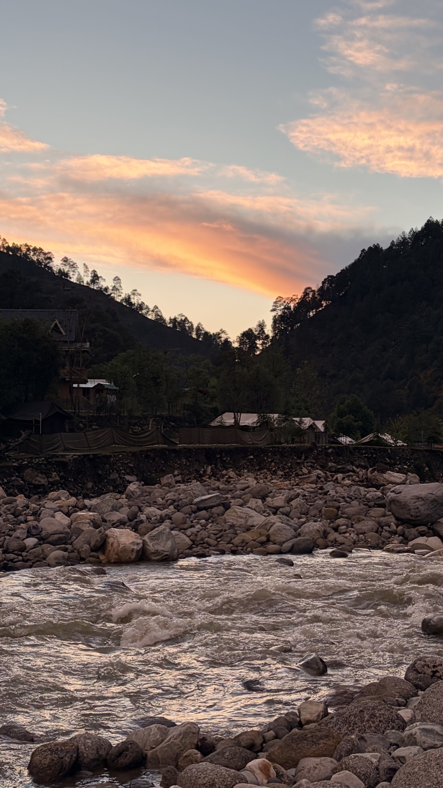 Sunset over the rocky Tirthan river, the sky burning orange