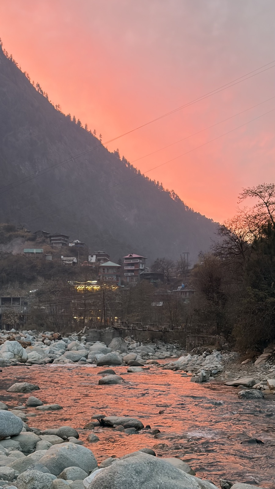 The Tirthan river at dusk beneath a pink sky